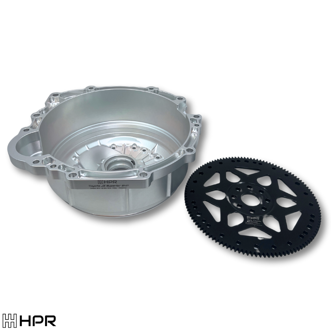 A billet bellhousing kit consisting of a metallic bellhousing and a black flexplate. Made of steel and aluminum , designed for use with 8HP transmissions in vehicles with Toyota JZ engine.